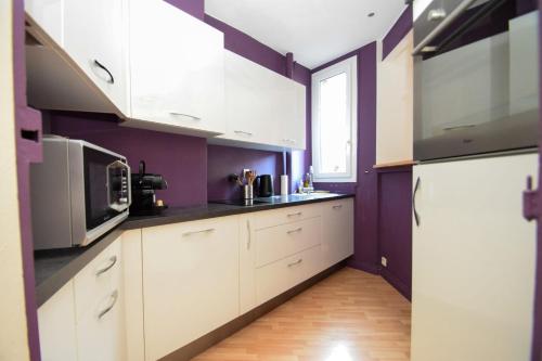 eine Küche mit weißen Schränken und lilafarbenen Wänden in der Unterkunft Top location near ParisSuperb cosy 2p apartment in Vincennes