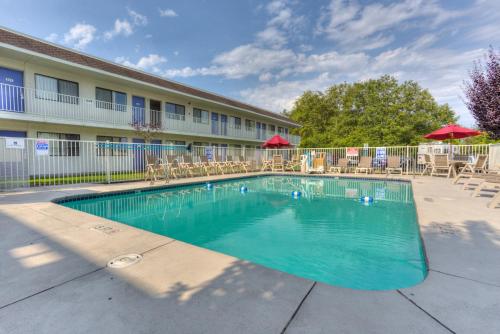 a swimming pool in front of a hotel with tables and chairs at Motel 6-Troutdale, OR - Portland East in Troutdale