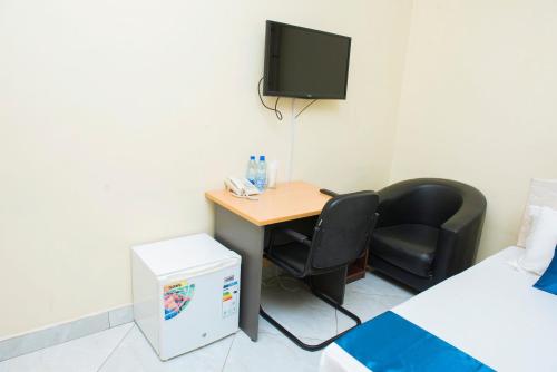 a room with a desk with two chairs and a tv at Airport Transit Lodges in Dar es Salaam