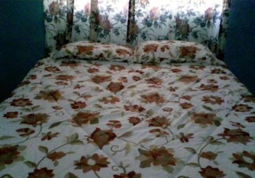 a bed with a floral comforter and pillows at Brisas de Borinquen in Aguadilla