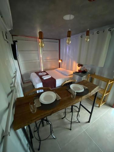 a room with a bed and a wooden table with plates on it at Pousada Cipó Container Chalés Privativos com lareira - Centro da cidade in Serra do Cipo