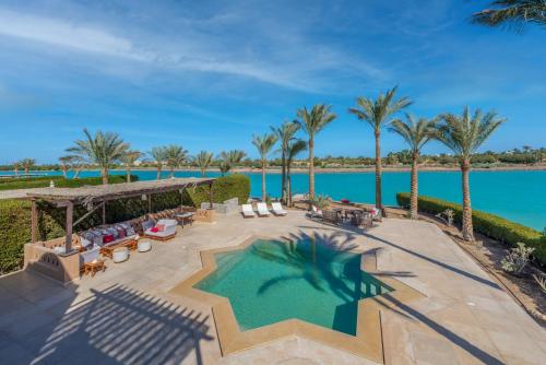 uma vista aérea de um resort com uma piscina e palmeiras em Chic 3BR Villa West Golf with Pool, Lagoon View & Guest House em Hurghada