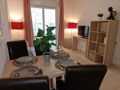 a dining room with a table and chairs and a television at Résidence de la Source by Euclenima in Salies-de-Béarn