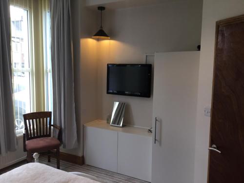 a hotel room with a tv on a wall at Dene House in Great Yarmouth