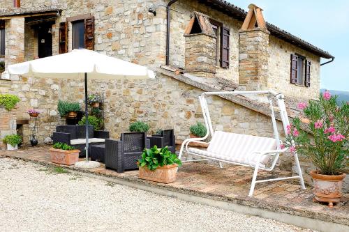 a patio with a white chair and an umbrella at Casale Le Orme in Todi