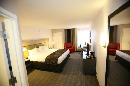 a hotel room with a bed and two red chairs at GreenTree Inn & Suites Phoenix Sky Harbor in Phoenix