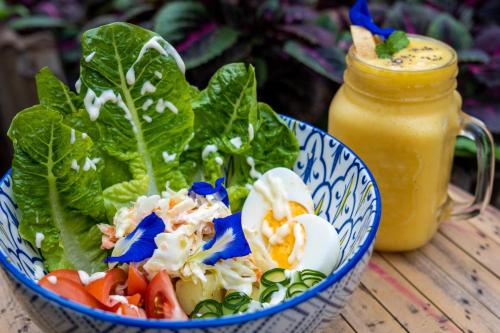 a salad in a blue and white bowl next to a jar of sauce at Mango Tree Eco-Hostel in Dauin
