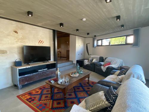 a living room with a couch and a tv at Le Héron - Gîte de charme clôturé, accès à la rivière - 6 ou 10 personnes in Fauvillers