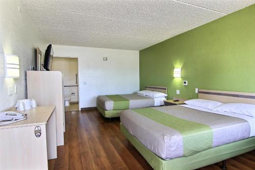 two beds in a hotel room with green walls at Motel 6 Austin, TX - Central Downtown UT in Austin