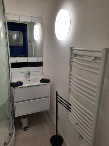 une salle de bain blanche avec un lavabo et un miroir dans l'établissement Résidence Beauvau – Numéro 3 - Centre de SARLAT, à Sarlat-la-Canéda