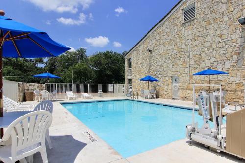 a swimming pool with chairs and blue umbrellas at Motel 6 Austin, TX - Central Downtown UT in Austin