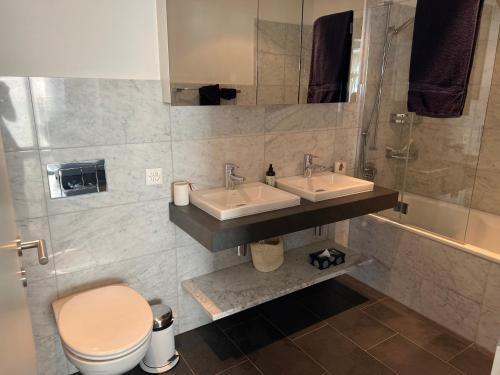ein Badezimmer mit zwei Waschbecken, einem WC und einer Dusche in der Unterkunft Apartment Bellania in Davos