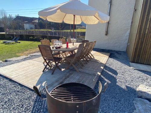 a table and chairs with an umbrella and a grill at Le Héron - Gîte de charme clôturé, accès à la rivière - 6 ou 10 personnes in Fauvillers