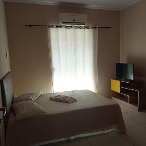 - une chambre avec un lit, une fenêtre et une télévision dans l'établissement Acomodação barata., à Campos dos Goytacazes
