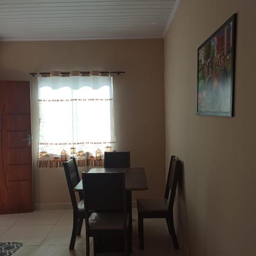 d'une salle à manger avec une table, des chaises et une fenêtre. dans l'établissement Acomodação barata., à Campos dos Goytacazes