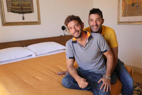 dwóch mężczyzn siedzących na łóżku w obiekcie DOMUS ALERIA Deluxe Rooms w mieście Sciacca
