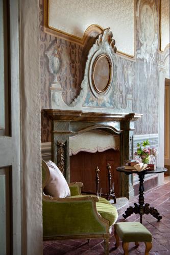 a living room with a fireplace and a green chair at Il Castello di San Michele in San Michele in Teverina