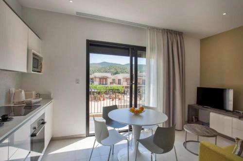 une cuisine et un salon avec une table et des chaises dans l'établissement Appartement E RONDINELLE 2, à Belgodère