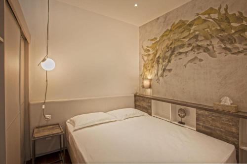 Un dormitorio con una cama blanca y una pintura en la pared en Appartement E RONDINELLE 2, en Belgodère