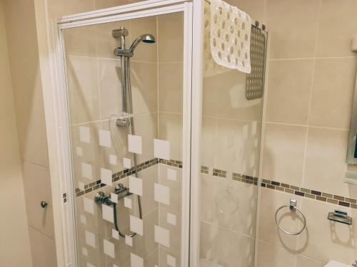 una doccia con porta in vetro in bagno di Parterre Holiday Apartments a Sandown