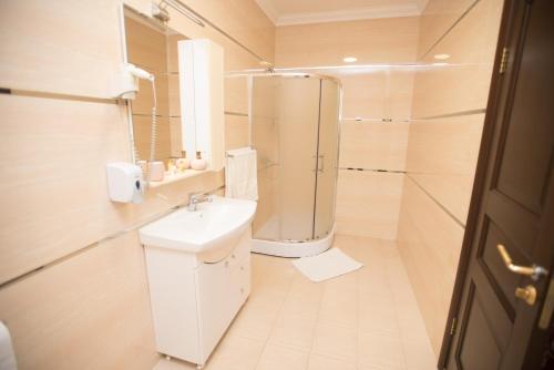 een witte badkamer met een wastafel en een douche bij Altin Palace in Komrat
