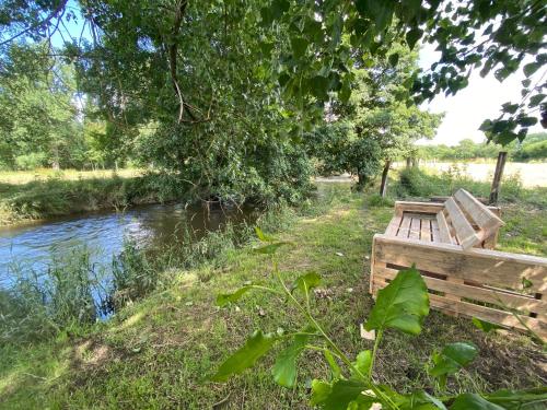 a wooden bench sitting next to a river at Le Héron - Gîte de charme clôturé, accès à la rivière - 6 ou 10 personnes in Fauvillers