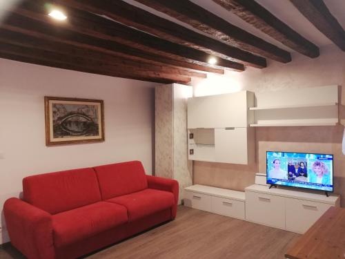 een woonkamer met een rode bank en een tv bij Ca al Campanile in Venetië
