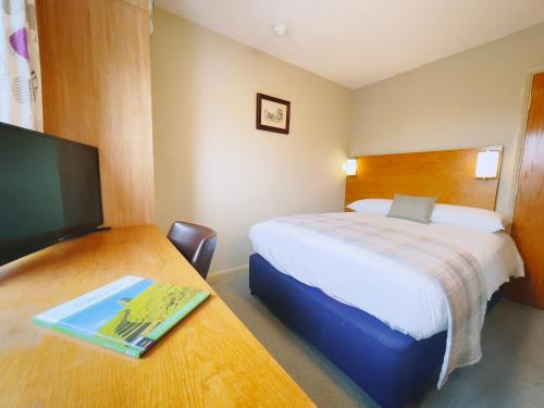 a bedroom with a bed and a desk with a tv at The Corner House Hotel in Taunton