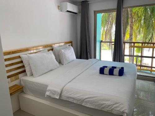 a bedroom with a large bed with a window at Lagoona Sunset in Maafushi