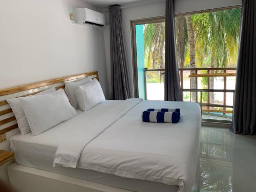 a bedroom with a large white bed with a window at Lagoona Sunset in Maafushi