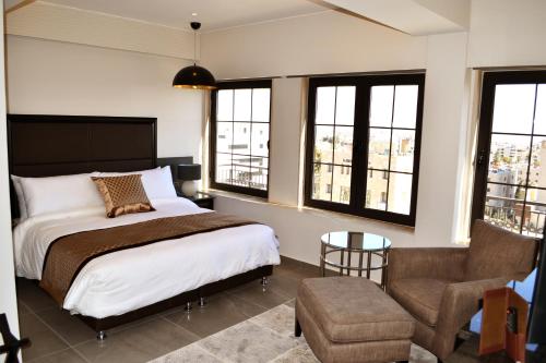 a bedroom with a bed and a chair and windows at Ambassador, a Boutique Hotel in Amman