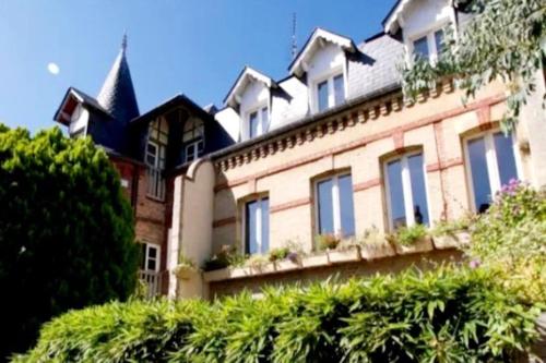 une grande maison avec des fenêtres et une tourelle dans l'établissement Villa Bon Accueil, à Deauville