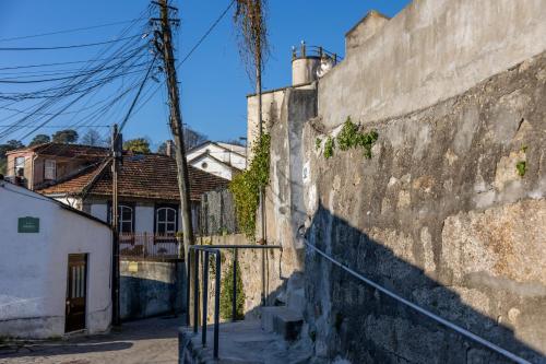 a stone wall next to a street with houses at House on a rustic Island At Campanha Trainstation in Porto