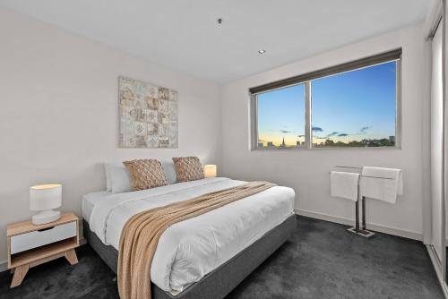 a white bedroom with a large bed and a window at Exclusive Stays - SXY in Melbourne