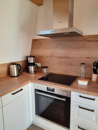 a kitchen with white cabinets and a stove top oven at Hof Ruemland Ferienwohnungen in Hollingstedt