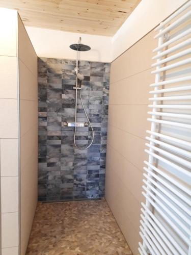 a walk in shower with a stone wall at Hof Ruemland Ferienwohnungen in Hollingstedt