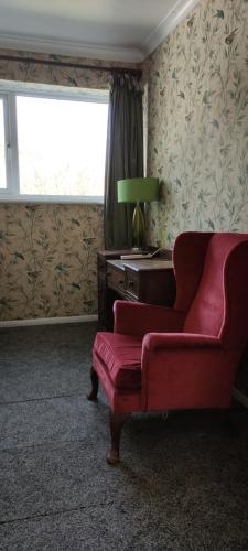 a living room with a red chair and a desk at Toad Hall Hostel in Machynlleth