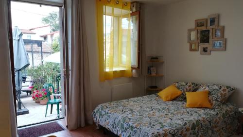Studio cosy Yssac-la-Tourette في Yssac-la-Tourette: غرفة نوم بسرير ومخدات صفراء ونافذة