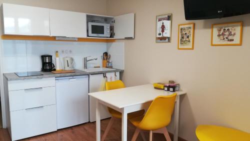 Studio cosy Yssac-la-Tourette في Yssac-la-Tourette: مطبخ صغير مع طاولة وكراسي صفراء