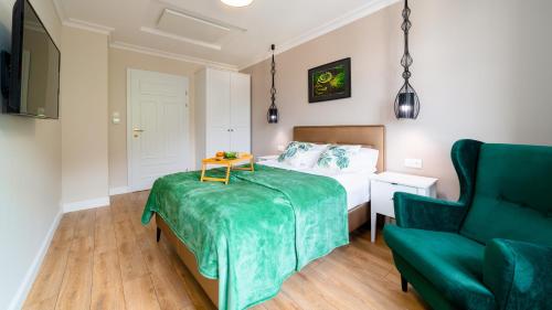 - une chambre avec un lit et une chaise verte dans l'établissement Royal Green - Apartamenty Deptak, à Karpacz
