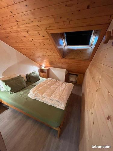 un grand lit dans une chambre avec un plafond en bois dans l'établissement Duplex la Plagne Montalbert, à Aime La Plagne