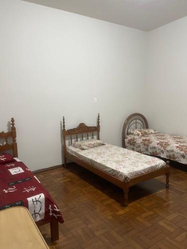 two beds in a room with white walls and wooden floors at Apartamento Temporada in Passos