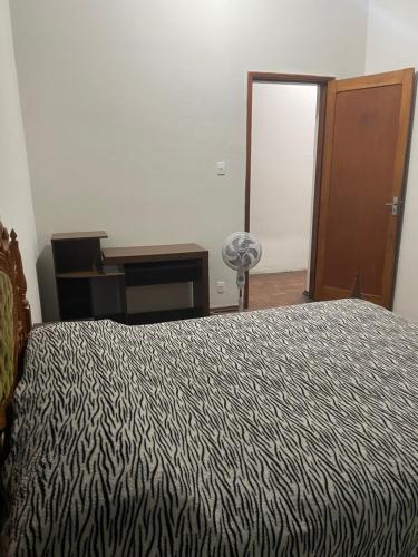 a bedroom with a bed and a desk and a door at Apartamento Temporada in Passos