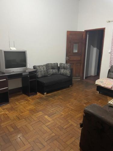 a living room with a couch and a television at Apartamento Temporada in Passos