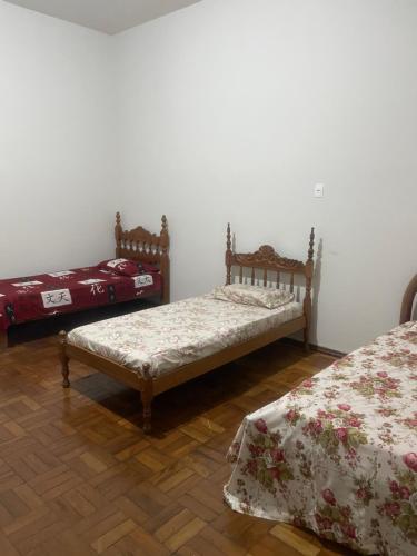 two beds in a room with white walls and wooden floors at Apartamento Temporada in Passos