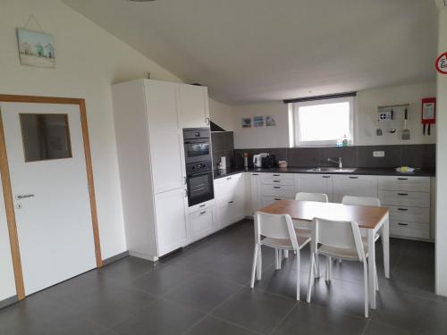 a kitchen with white cabinets and a table and chairs at de blinker in Knokke-Heist