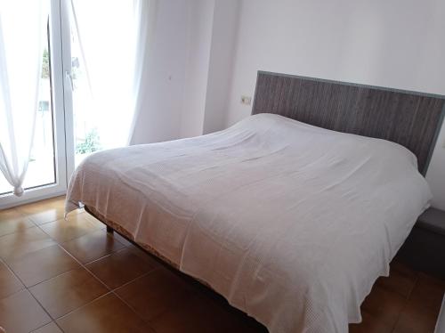 a white bed in a room with a large window at Can Eugeni in L'Escala