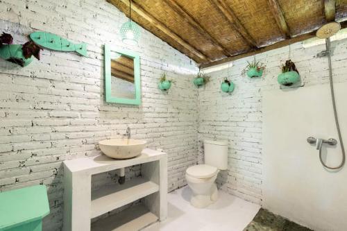 a bathroom with a sink and a white brick wall at Bali Brothers Guesthouse in Dalung