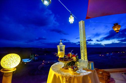 a table with a lamp and a bowl of flowers on it at Agafay Pearl Camp Marrakech in Marrakech