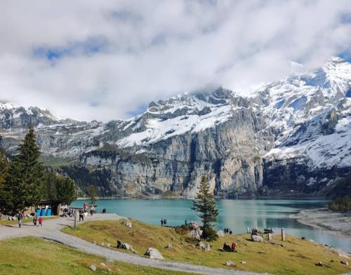 a group of people standing around a lake in front of a mountain at Mountain Oasis Apartment Kandersteg-Adelboden in Kandergrund